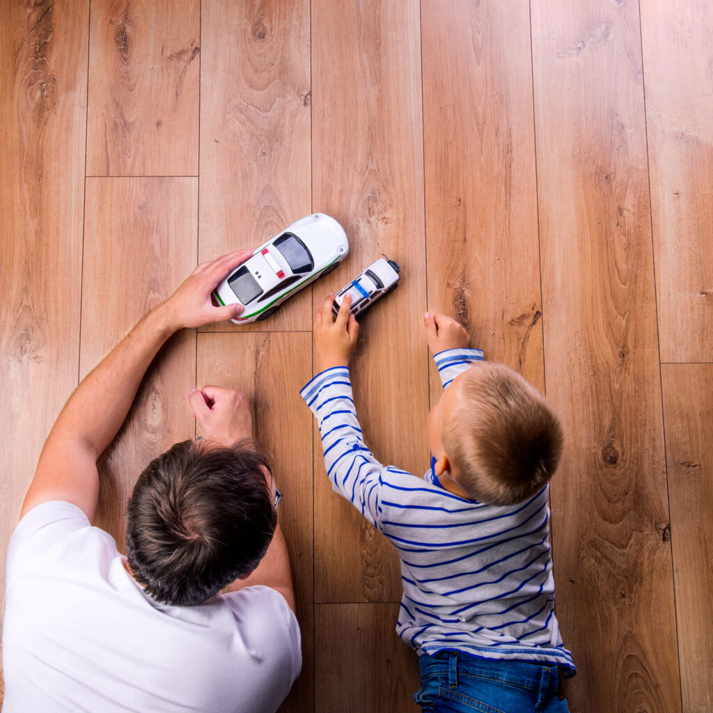 Dad and son playing with toy car | Flooring By Design NC
